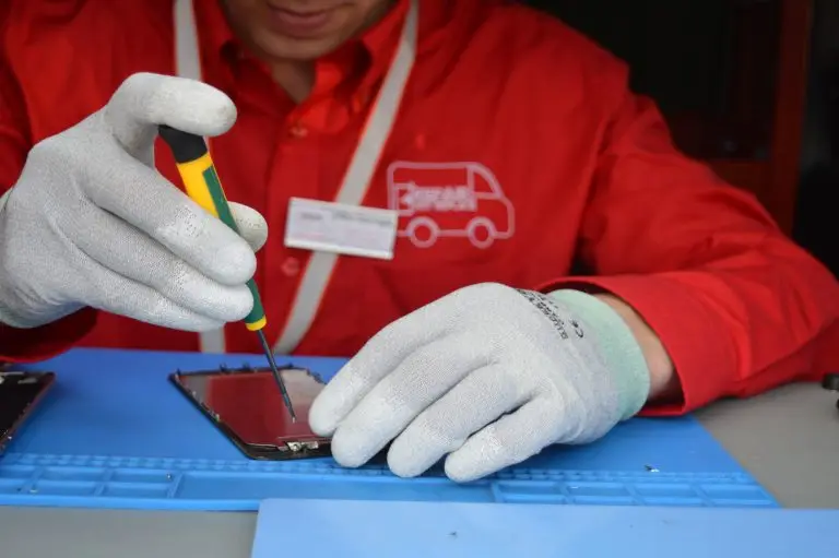 Man fixing mobile phone, screwdriver in hand